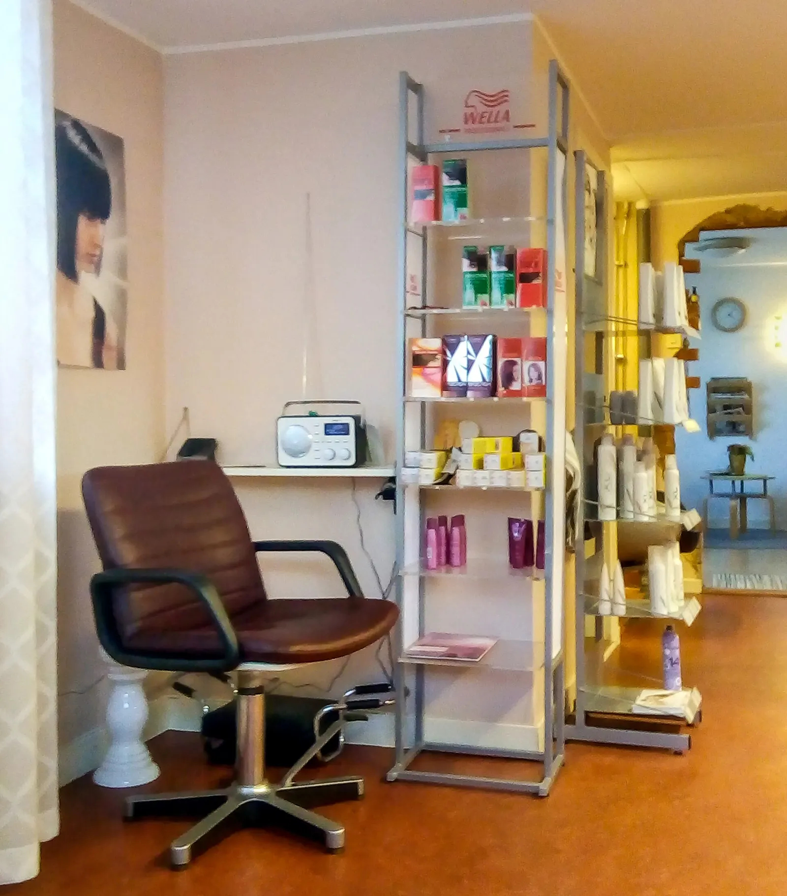 A small hair salon with one styling chair, a mirror and shelves of hair products